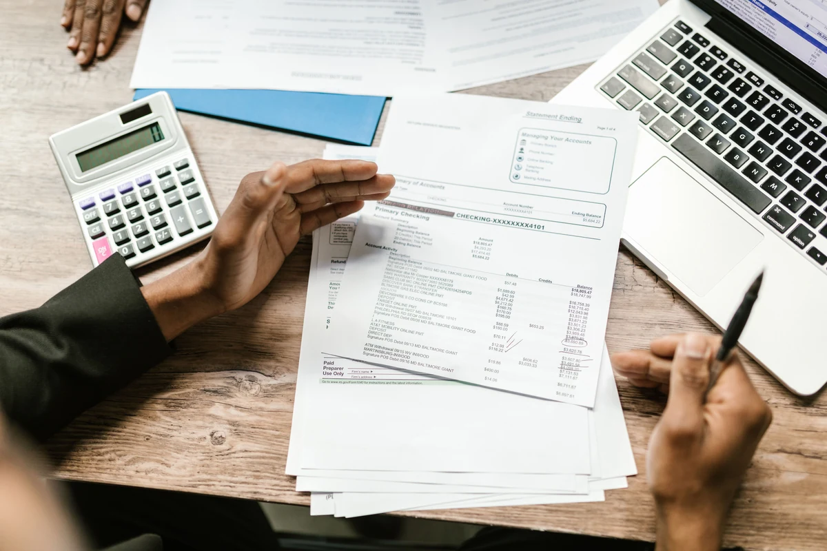 Financial paperwork beside a calculator and laptop
