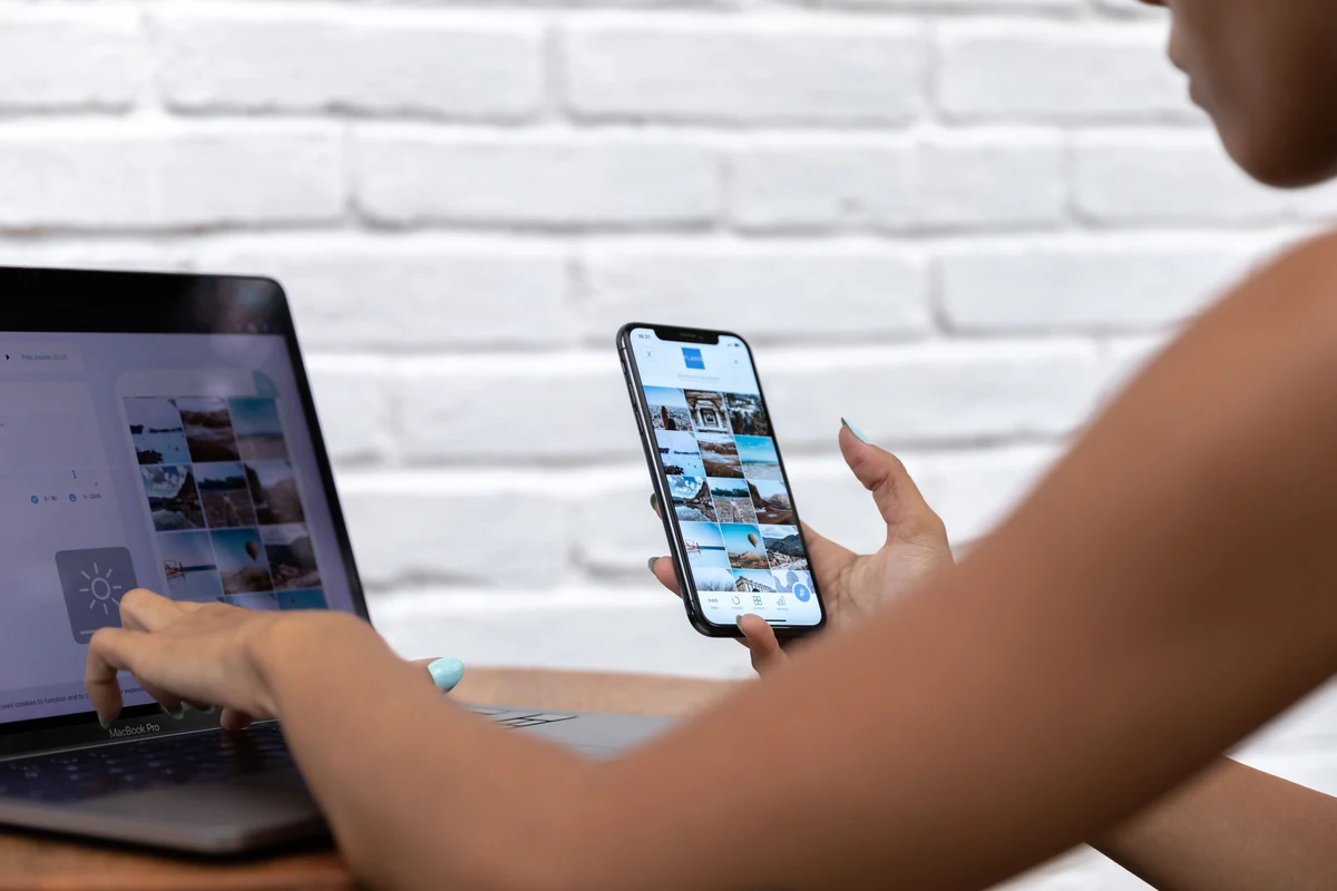 A person reviewing content on a phone and laptop