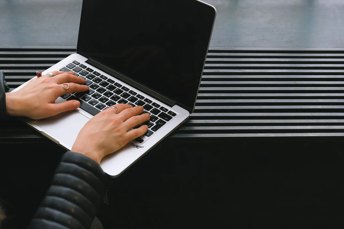 Hands typing on a laptop at a desk